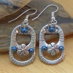 two pairs of silver and blue beaded earrings sitting on top of a wooden table