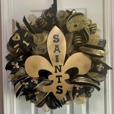 a new orleans saints wreath on the front door is decorated with gold and black ribbons