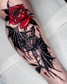 a tattoo on the leg of a man with a rose and two skulls in it