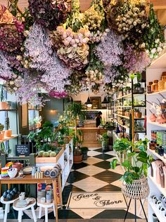 a flower shop filled with lots of different types of flowers hanging from the ceiling and potted plants