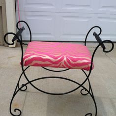 a pink and black bench sitting in front of a garage door with a red rug on it