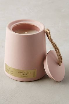 a pink candle holder with a rope wrapped around it and a round container in the middle