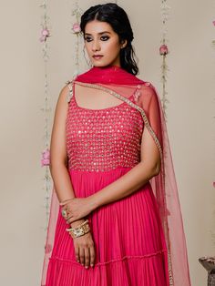 A two-piece fuchsia pink mirror anarkali set from the Redpine Designs collection. This pretty fuchsia pink mirror anarkali is paired with a net embroidered dupatta. The fuchsia pink color with mirror, cutdana, shell, kasab, sequins work enhances the graceful georgette anarkali set. The fuchsia pink anarkali has beautiful pleats, and frills with flare style. The outfit features embroidered shell work straps, heavy mirror embroidery and a scoop neckline. Pink Anarkali Set With Dori Work, Designer Pink Anarkali Set With Gota Work, Pink Chandbali Salwar Kameez In Georgette, Designer Wear Pink Anarkali Set With Gota Work, Designer Pink Anarkali Set For Diwali, Pink Anarkali Set For Diwali, Pink Chanderi Dress With Mirror Work, Pink Anarkali Set With Dupatta, Pink Bollywood Anarkali Set With Gota Work