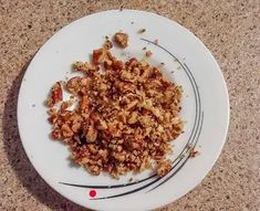 a white plate topped with food on top of a counter next to a knife and fork