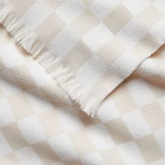 a white and beige checkered blanket with fringes on the edges, close up