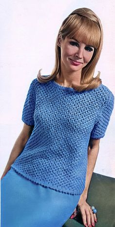 a woman wearing a blue knitted top and skirt posing for the camera with her hand on her hip