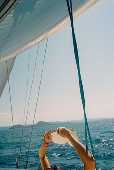 a woman sitting on the back of a boat while holding her hat in front of her face