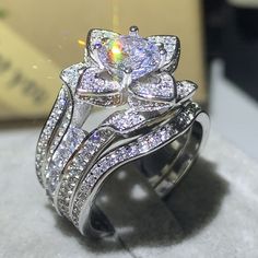 a close up of two rings with diamonds on top of each other and the ring has a flower shaped center surrounded by smaller white stones