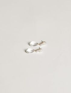 two pairs of silver earrings on a white surface