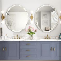 there are two mirrors on the wall above the sinks in this bathroom with blue cabinets and marble counter tops