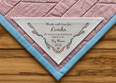 a pink and blue quilted triangle with the words made with love for linda on it