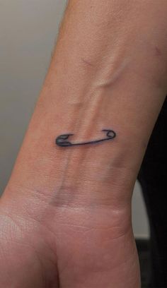 a small wrist tattoo with an arrow on the left side of the wrist and a black outline