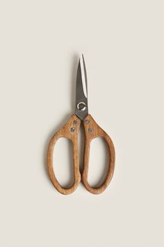 a pair of wooden scissors sitting on top of a white table next to each other