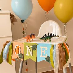 a baby's first birthday party with balloons and decorations, including a dinosaur banner