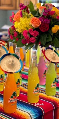 several bottles of lemonade are sitting on a table with straw hats and flowers in the background