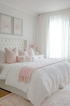 a white bed with pink pillows and blankets