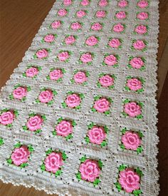 a crocheted table runner with pink roses on it