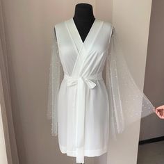 A amazing bridal robe with pearls on the sleeves for lovers of sophisticated, unusual beauty. This is a great combination of uncompromising luxury and absolute comfort. Thanks to the belt that comes with the kit and the V-neck, graceful folds of fabric stretch the silhouette and you will look noticeably slimmer🤗.Made in Ivory will be the perfect outfit for the bride and in the future will be the pearl of your wardrobe 👗. Only Handmade ✂️.The same only long to the floor: https://www.etsy.com/li Bridal Robes Getting Ready, Kimono Bride, Wedding Kimono Robe, White Bridal Robe, Long Bridal Robe, Bride Dressing Gown, Bridal Dressing Gown, Boho Maternity Dress, Bridal Nightgown