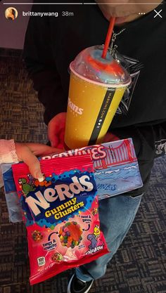 a person holding a bag of nerds and a drink with a straw in it