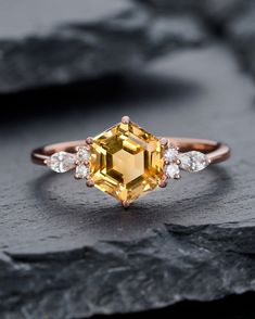 an engagement ring with a yellow diamond surrounded by white diamonds on top of a rock