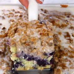 a close up of a cake in a pan with blueberries and cream on top