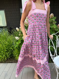 This is it! THE dress of the summer! Meet Maisie, our newest cotton block print maxi dress in a Pink Posey print. She’s full of sweet details like a tiered skirt, and contrasting striped banding. The bow straps are adjustable for the perfect fit, and it features a smocked back panel for comfort. Did we mention it has POCKETS!? Whether you're sipping lemonade on the porch or hitting up a summer wedding or soirée, this dress is a fun, versatile addition to your closet. Throw it on with sneakers or Tiered Cotton Sundress With Floral Print, Cotton Tiered Floral Print Sundress, Tiered Cotton Floral Sundress, Cotton Tiered Floral Sundress, Cotton Tiered Dress For Vacation, Cotton Dress With Tie Straps And Tiered Skirt, Cotton Tiered Sundress For Vacation, Summer Cotton Dress With Tiered Skirt, Cotton Tiered Skirt Maxi Dress For Garden Party