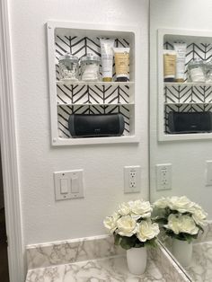 a bathroom sink with two mirrors above it and flowers in the vase on the counter