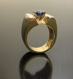 DeKara Designs Clearance Metal- 14K Yellow Gold, .583. 15.6 Grams. Stones- 1 Round Ceylon Blue Sapphire 1.12 Carats, 12 Princess Cut Diamonds G-H Color VS2 Clarity 0.60 Carats. Size- Ring is a 6. FREE SIZING Art Deco Inspired Handmade 14K Yellow Gold Ceylon Blue Sapphire Diamond Ring. This ring is inspired by the Art Deco era with an enticing fiery Round Ceylon Blue Sapphire that is set in between six prongs. There are six professionally channel set diamonds on each side of the center sapphire. Elegant Sapphire Ring With Tanzanite And Polished Finish, Luxury Tanzanite Yellow Gold Ring, Luxury Yellow Gold Tanzanite Ring, Luxury Trillion Cut Sapphire Ring For Formal Events, Luxury Trillion Cut Sapphire Ring For Formal Occasions, Formal Rings With Trillion Cut Center Stone, Trillion Cut Sapphire Ring With Diamond For Formal Occasions, White Gold Trillion Cut Sapphire Ring For Formal Occasions, Modern Yellow Gold Sapphire Ring For Formal Events