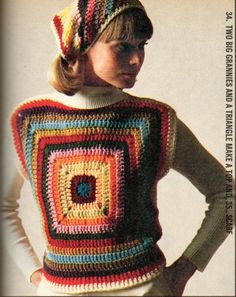 a woman wearing a multicolored crocheted sweater and hat with her hands on her hips