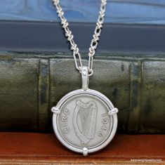 This is a custom order item. Your order will ship within 3-5 business days of payment confirmation. The coin pendant in the listing photos is an example of the finished piece. Excluding the year on the coin, your coin pendant will be the same design as the pictured pendant. Each pendant setting is made by hand (not a machine), and no two coins are exactly alike. If you are looking for a specific year, let me know, I may have it in my collection. This Irish Three Pingin rests in a handcrafted set Classic Sterling Silver Necklace With Coin Pendant, Hallmarked Coin Shaped Sterling Silver Necklaces, Heirloom Silver Necklace With Coin Pendant, Handmade Coin-shaped Sterling Silver Necklace, Handmade Sterling Silver Necklace For Commemoration, Heirloom Sterling Silver Round Pendant Necklace, Heirloom Sterling Silver Pendant Necklace, Classic Hallmarked Sterling Silver Custom Necklace, Antique Stamped Sterling Silver Necklace