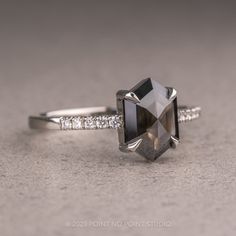 a black and white diamond ring sitting on top of a gray surface with diamonds around it