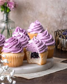 several cupcakes with purple frosting on a plate