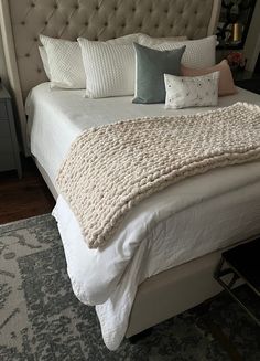 a bed with white sheets and pillows on top of it