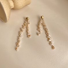 Introducing our exquisite Pearl Drop Earrings, a true masterpiece in asymmetrical elegance. These earrings are meticulously handcrafted using a combination of real freshwater pearls and 18 karat yellow gold vermeil. The unique wavy design, with its beige pearls and subtle, blurry details, evokes a sense of graceful fluidity. Embrace the artistry of asymmetry and add a touch of ethereal beauty to your style with these light white wonders. Yellow Gold Pearl Dangle Earrings, Delicate Gold Pearl Chandelier Earrings, Gold Plated Pearl Chain Dangle Earrings, Dangle Earrings With Baroque Pearl Chain, Gold Pearl Chandelier Earrings Delicate Style, Gold Pearl Chandelier Earrings In Delicate Style, Gold Dangle Pearl Earrings, Graceful Pearl Dangle Earrings, Gold Pearl Dangle Linear Earrings