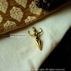 a gold brooch sitting on top of a white cloth next to a decorative pillow