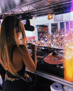 a woman with headphones standing in front of a dj's turntable