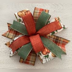 a close up of a bow on top of a white wooden table with red and green ribbon