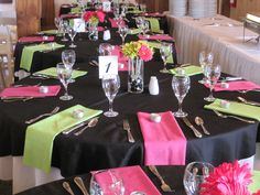 the tables are set with black and pink napkins, silverware, and wine glasses