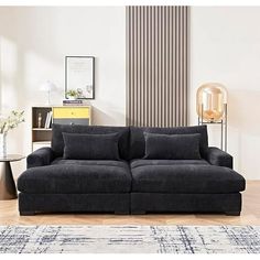 a black couch sitting on top of a wooden floor next to a table and lamp