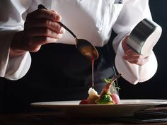 a chef is drizzling sauce on a dish