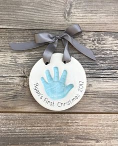 a ceramic ornament with a handprint on it and a ribbon around the tag