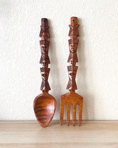 two wooden utensils with designs on them are sitting next to each other in front of a white wall