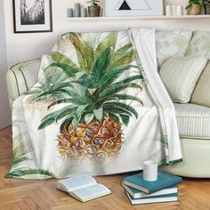 a couch covered in a blanket with a pineapple on it next to some books