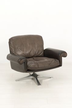 a brown leather chair sitting on top of a white floor