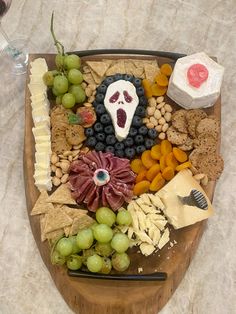 a wooden platter filled with cheese, crackers, grapes and other food items