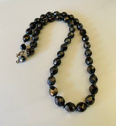 This classic nice quality 18 inch 7mm faceted jet black bead necklace is a classic closet basic. The faceted beads have seed bead spacers and wire strung smaller beads near the clasp to keep the back from being bulky. The necklace is sturdy with a gold tone lobster claw closure. The necklace is a classic inches long. This necklace is a great closet basic in wonderful vintage condition. The beads have a bright carnival sheen. I specialize in finding fun wearable vintage jewelry. Please browse my Classic Faceted Beads Necklace For Gift, Elegant Hematite Beaded Necklaces, Black Necklace With Oval Spacer Beads, Formal Adjustable Beaded Necklace With Faceted Beads, Black Faceted Round Beaded Necklaces, Black Faceted Beaded Necklaces, Elegant Faceted Oval Beads, Classic Faceted Round Bead Necklaces, Formal Beaded Necklaces With Faceted Beads