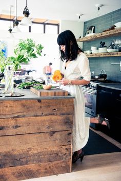 a woman standing in a kitchen preparing food on top of a wooden counter next to an oven