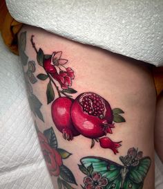 a woman's thigh with pomegranates on it and butterflies around her