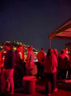 people standing on top of a roof at night with the city lights in the background