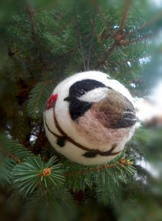 a needled ornament hanging from a christmas tree with a bird on it